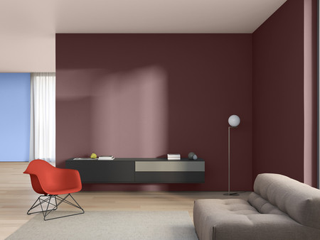 Nowoczesny salon z czerwono-brązową ścianą. Po lewej stronie stoi wygodna szara sofa, a po prawej czerwone krzesło o zakrzywionym kształcie. Na ścianie wisi prosta czarna komoda, na której leży kilka przedmiotów.