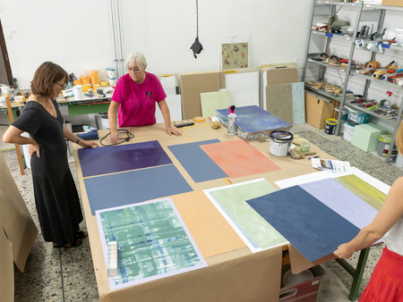 Drei Personen begutachten Muster der Trendfarben 2025 auf einem Tisch in einem Atelier