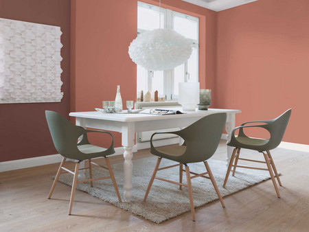 Modernes Esszimmer mit weißem Tisch, olivfarbenen Stühlen, Terrakottawänden und kunstvoller Beleuchtung