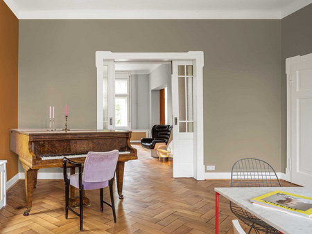 Elegantes braunen Wohnzimmer-Interieur mit Flügel, Fischgrätenboden und Türen zum Nebenzimmer