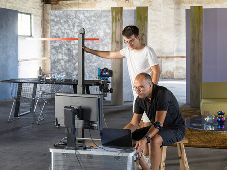 Fotograf und Assistent sehen sich durch Arbeitspcs den Aufbau des Interiors in der alten Fabrik für das Shooting der Kampagne an