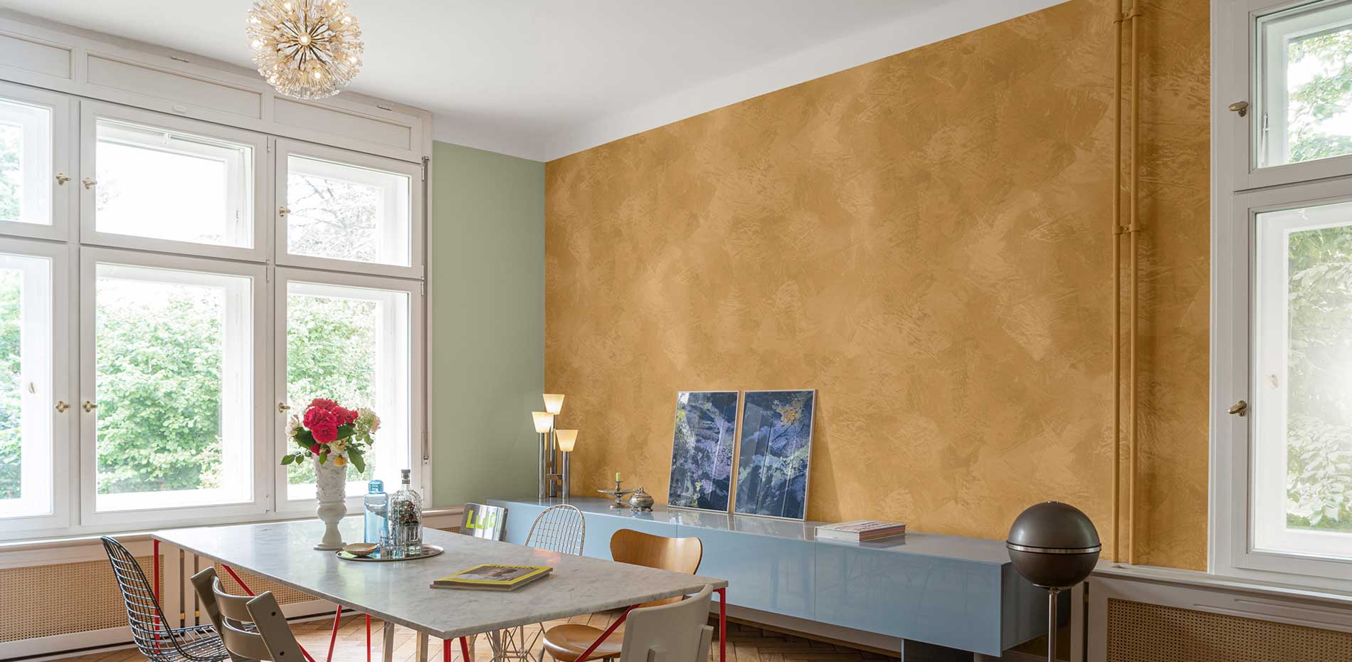 Modernes Zimmer mit großen Fenstern, senffarbener Akzentwand, Marmortisch, Designerstühlen und hängendem Kronleuchter, basierend auf dem Konzept 'Farbkombination + Oberfläche = Raumdesign