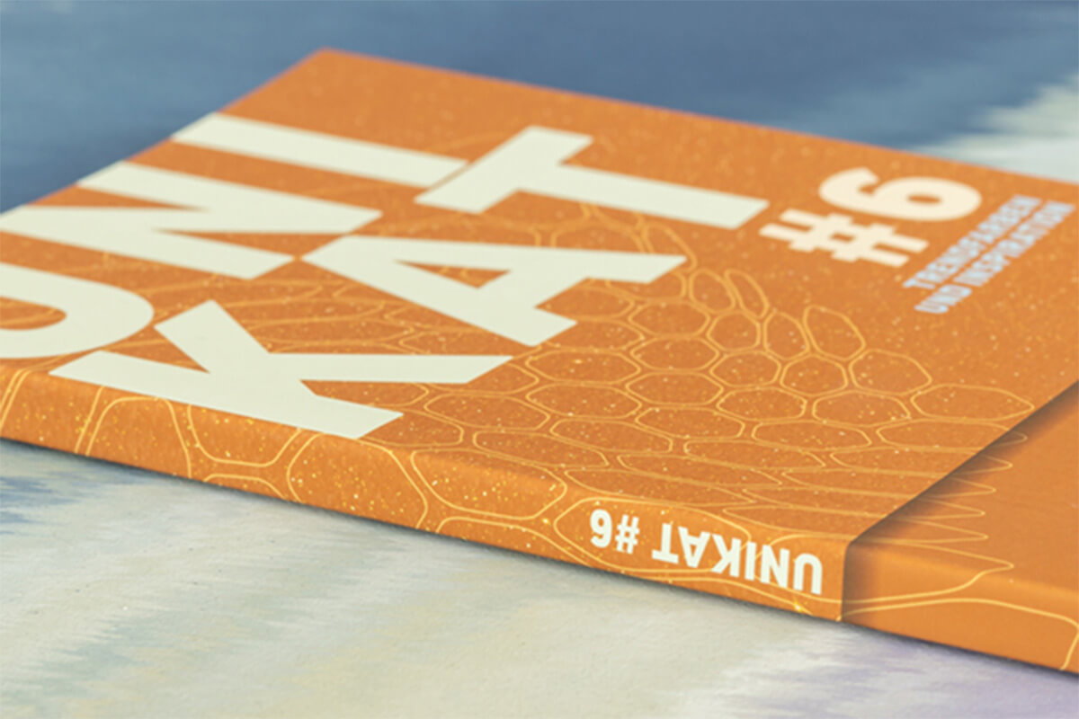 Orangenes Trendbuch 2024 Unikat #6 auf einem creme-blauen Tisch.